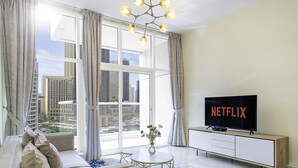 A modern living room with a large window, a flat-screen TV, and a view of a marina. - LUX  The Continental Marina Suite (Dubai)