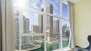 A room with a large window offering a view of a marina and high-rise buildings. - LUX  The Continental Marina Suite (Dubai)