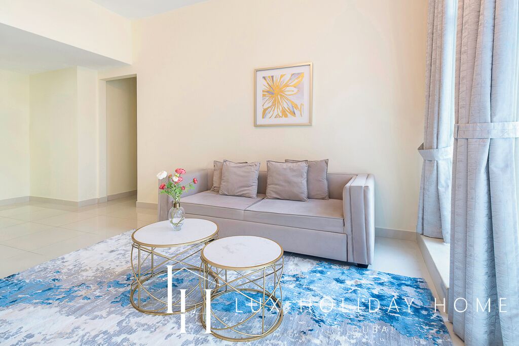 A modern living room with a sofa, two round coffee tables, and a decorative vase.