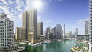 A modern cityscape with high-rise buildings, a marina with boats, and a clear sky. - LUX  The Continental Marina Suite (Dubai)