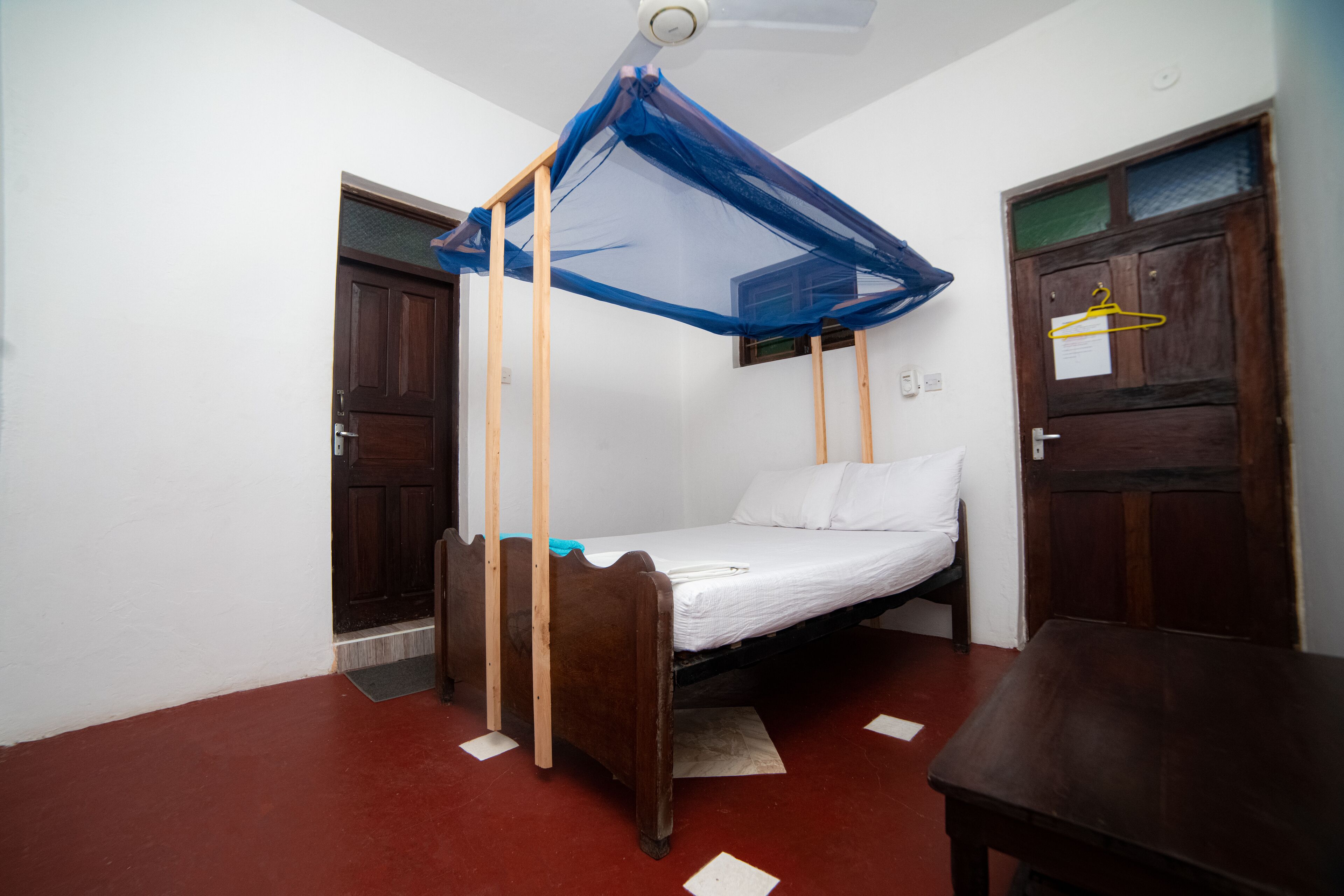 A room with a single bed, wooden furniture, and a ceiling fan.