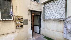 Un vialetto stretto con l'ingresso di un edificio, una cassetta postale e un cancello di sicurezza.