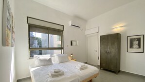 Una camera da letto con un letto, un armadio, una finestra con persiane e un condizionatore d'aria a parete.