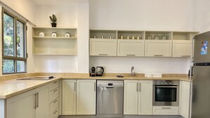 Una cucina moderna con mobili bianchi, lavastoviglie in acciaio inossidabile, forno e frigorifero.