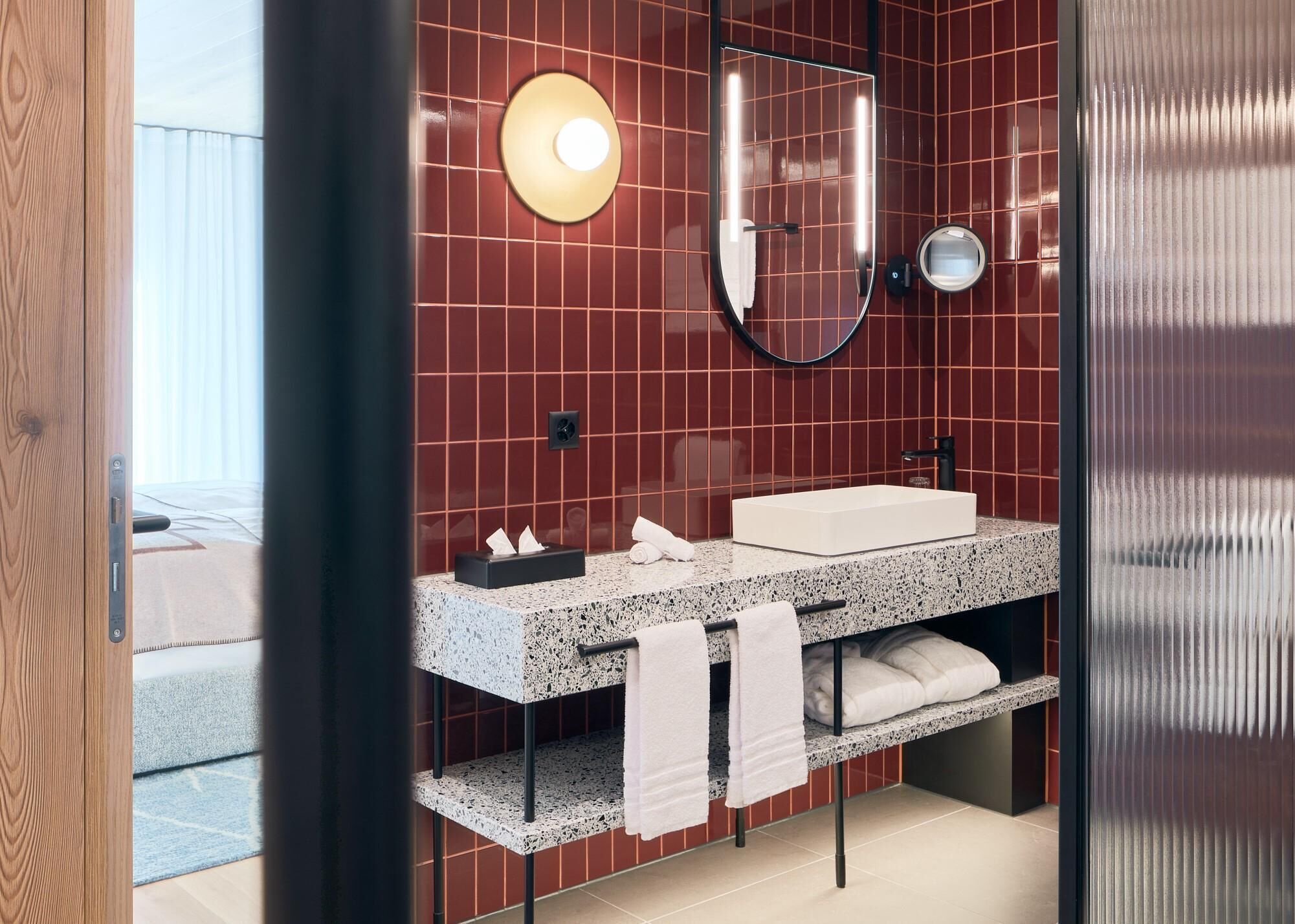 A modern bathroom with a granite countertop, a white sink, and a large mirror.