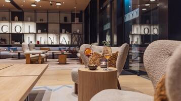 Un interior moderno con sofás, una mesa redonda de madera y una vitrina de cristal. En la pared, la palabra 'COLINA'.