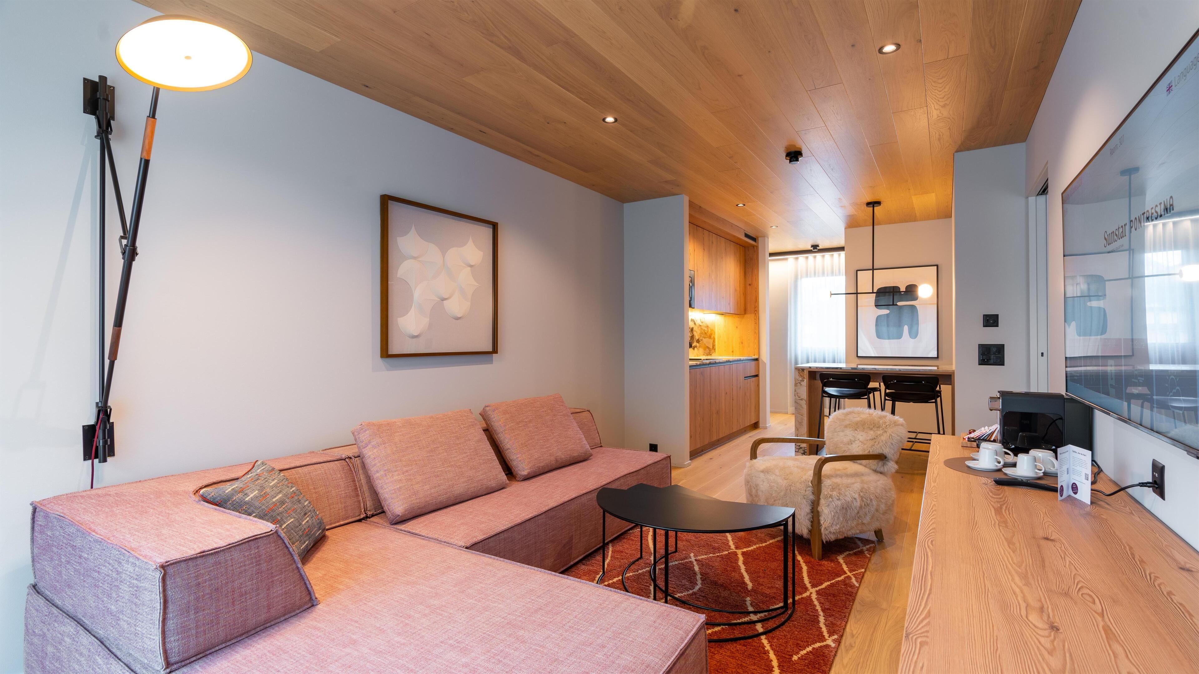 A modern living room with a sofa, a coffee table, and a dining area with chairs.
