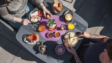Ett runt bord med olika sorters frukostmat, inklusive croissanter, ägg och en kaffedryck.