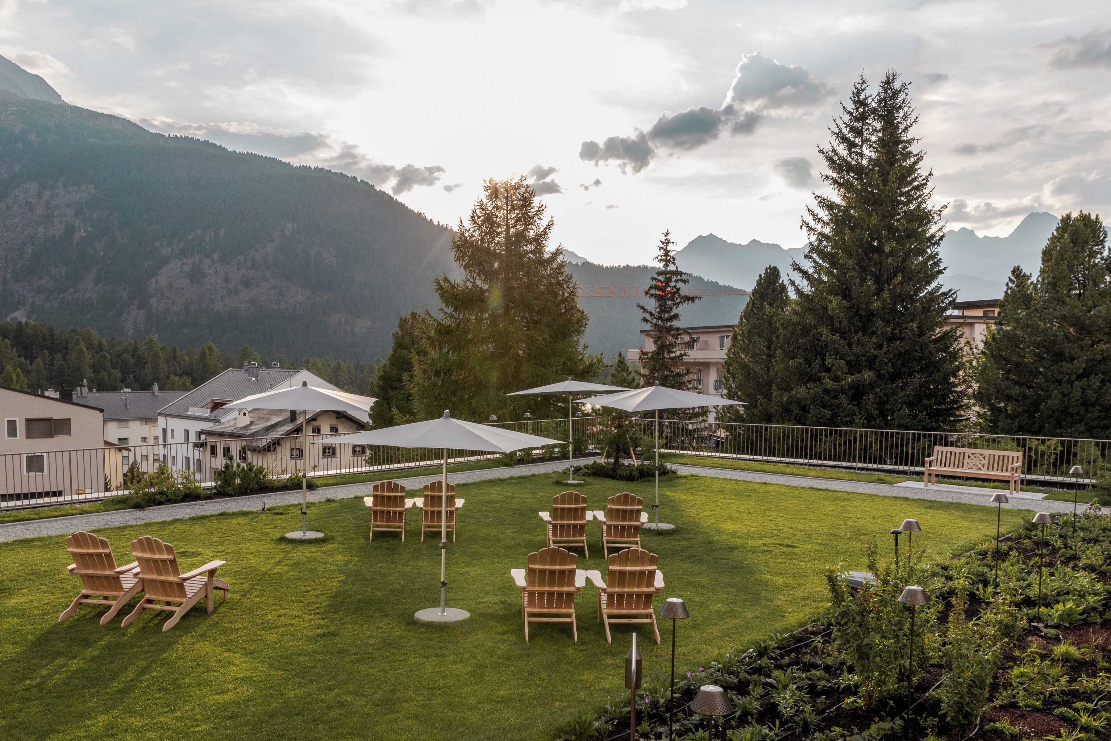 A well-maintained lawn with outdoor seating, a wooden bench, and a view of mountains in the background.