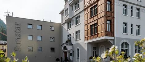 Un hotel con fachada moderna, un cartel que dice "Sunstar" y un patio con área de estacionamiento.