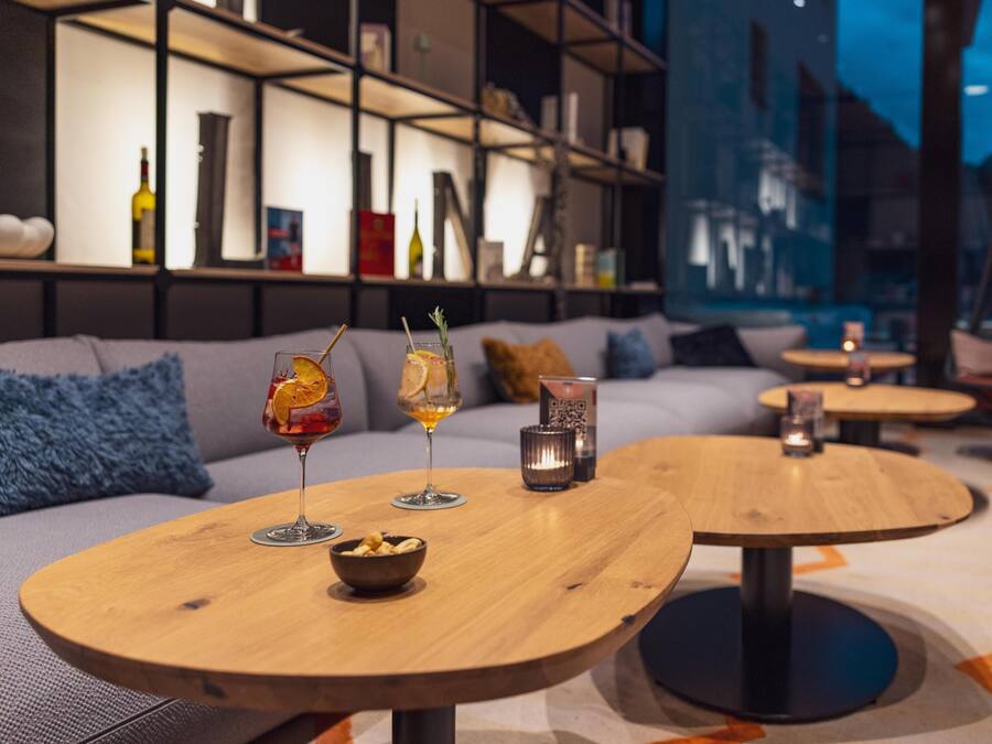 Un área de estar moderna con mesas redondas de madera, un sofá y una estantería.