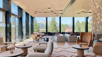 Un amplio salón con asientos cómodos, ventanas grandes que ofrecen vistas a las montañas e iluminación moderna.
