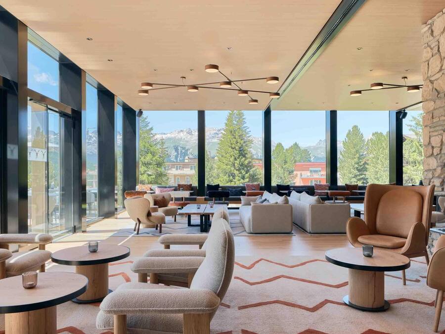 Un amplio salón con asientos cómodos, ventanas grandes que ofrecen vistas a las montañas e iluminación moderna.