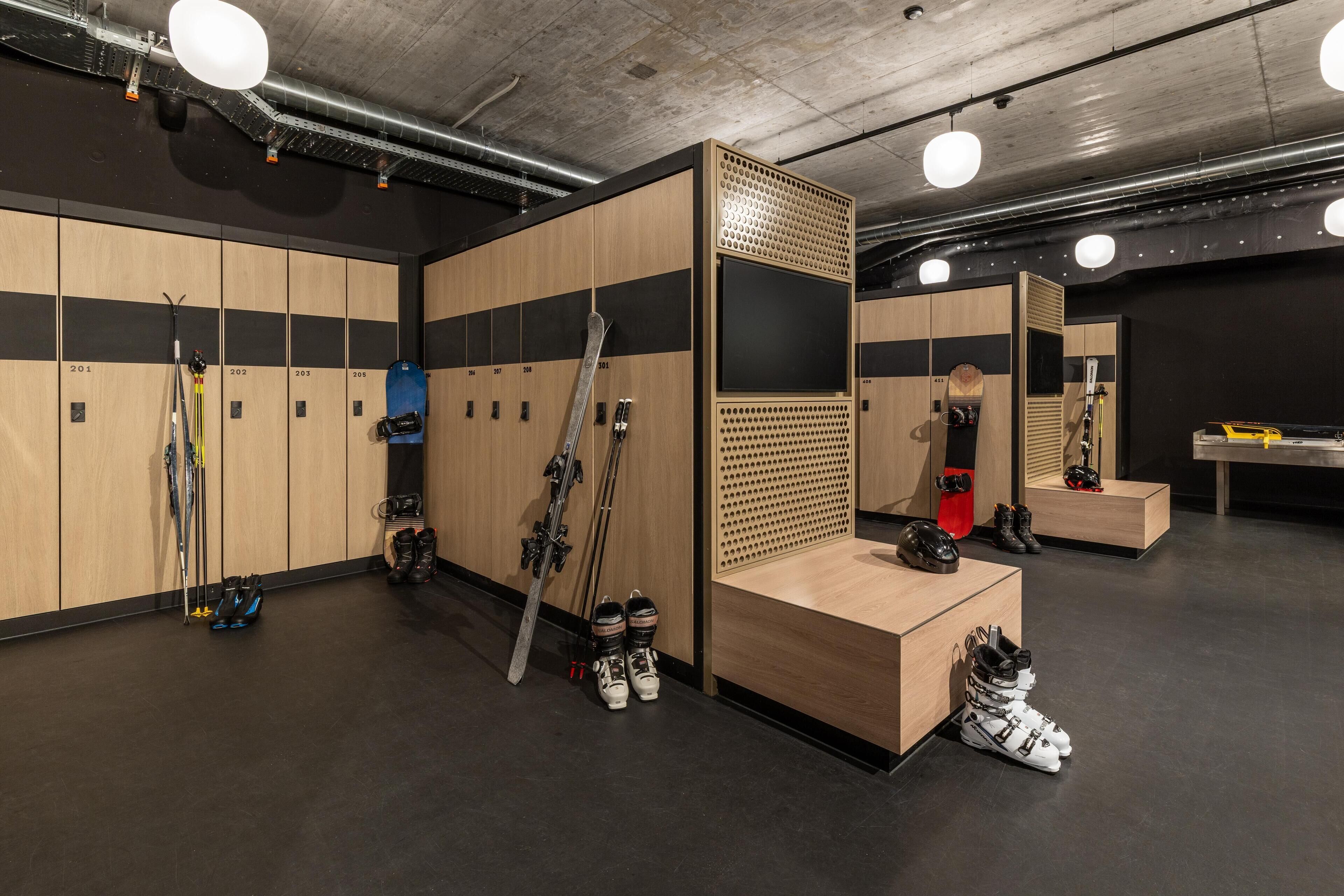 A ski locker room with wooden lockers, ski racks, and a mirror.