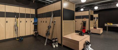 A ski locker room with wooden lockers, ski racks, and a mirror.