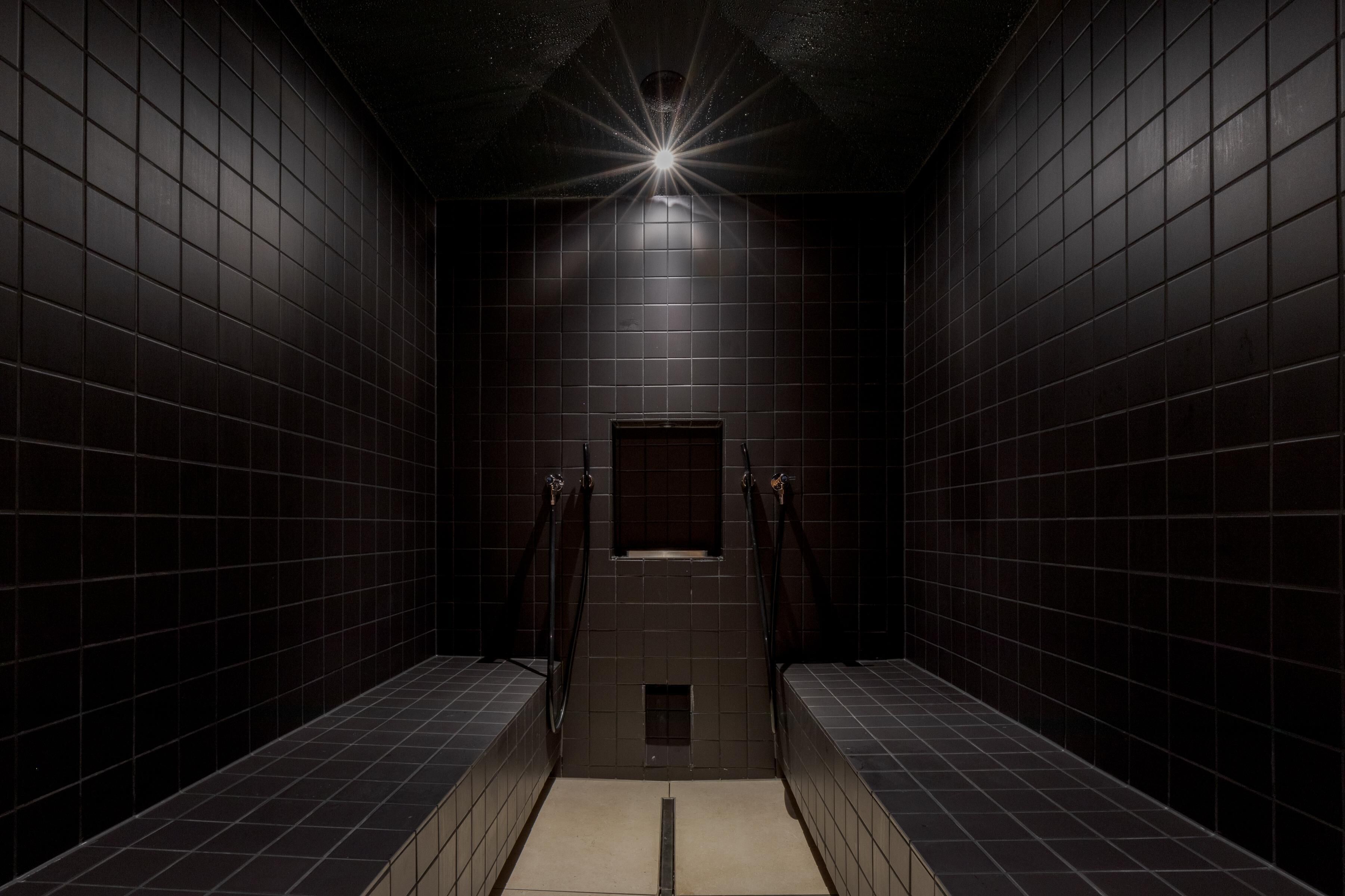A narrow, tiled hallway with a central light fixture and a small window.
