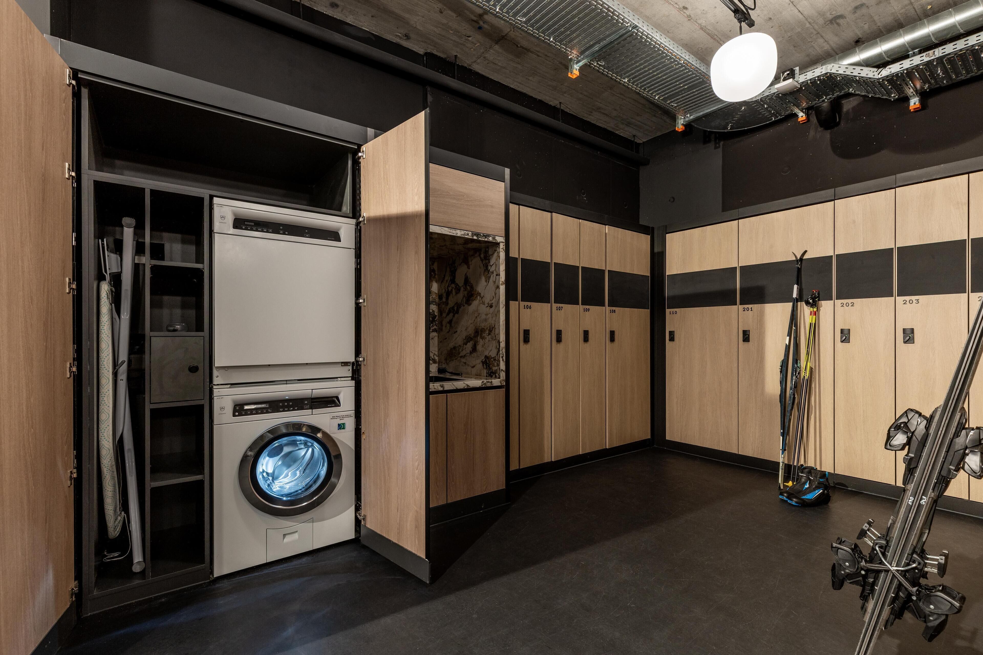A laundry room with a washing machine, dryers, and a ski rack.