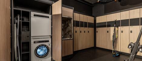 A laundry room with a washing machine, dryers, and a ski rack.