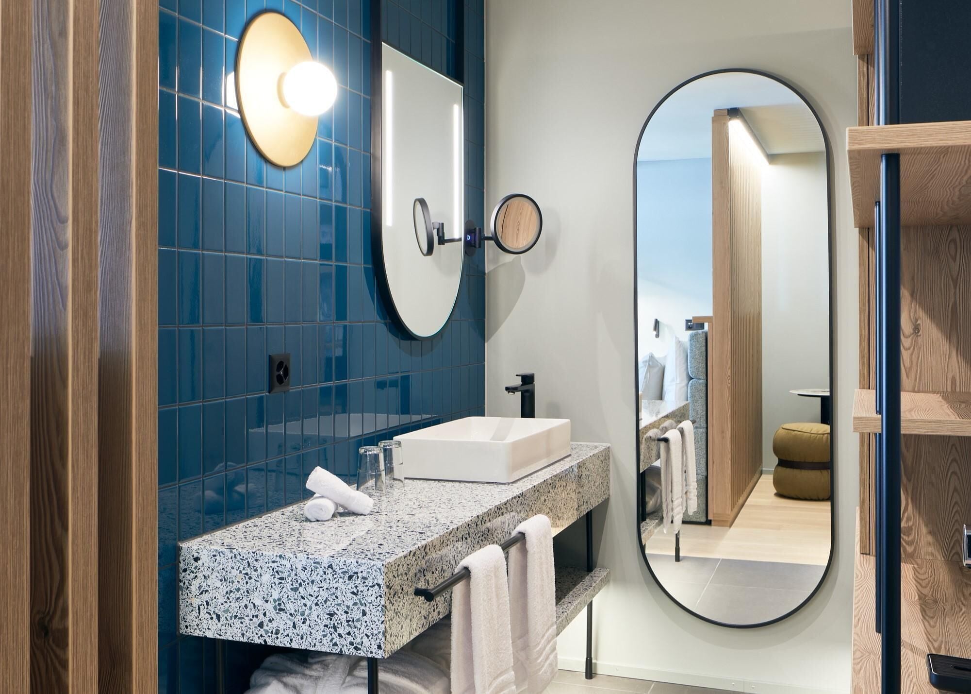 A modern bathroom with a granite countertop, a white sink, and a large mirror.