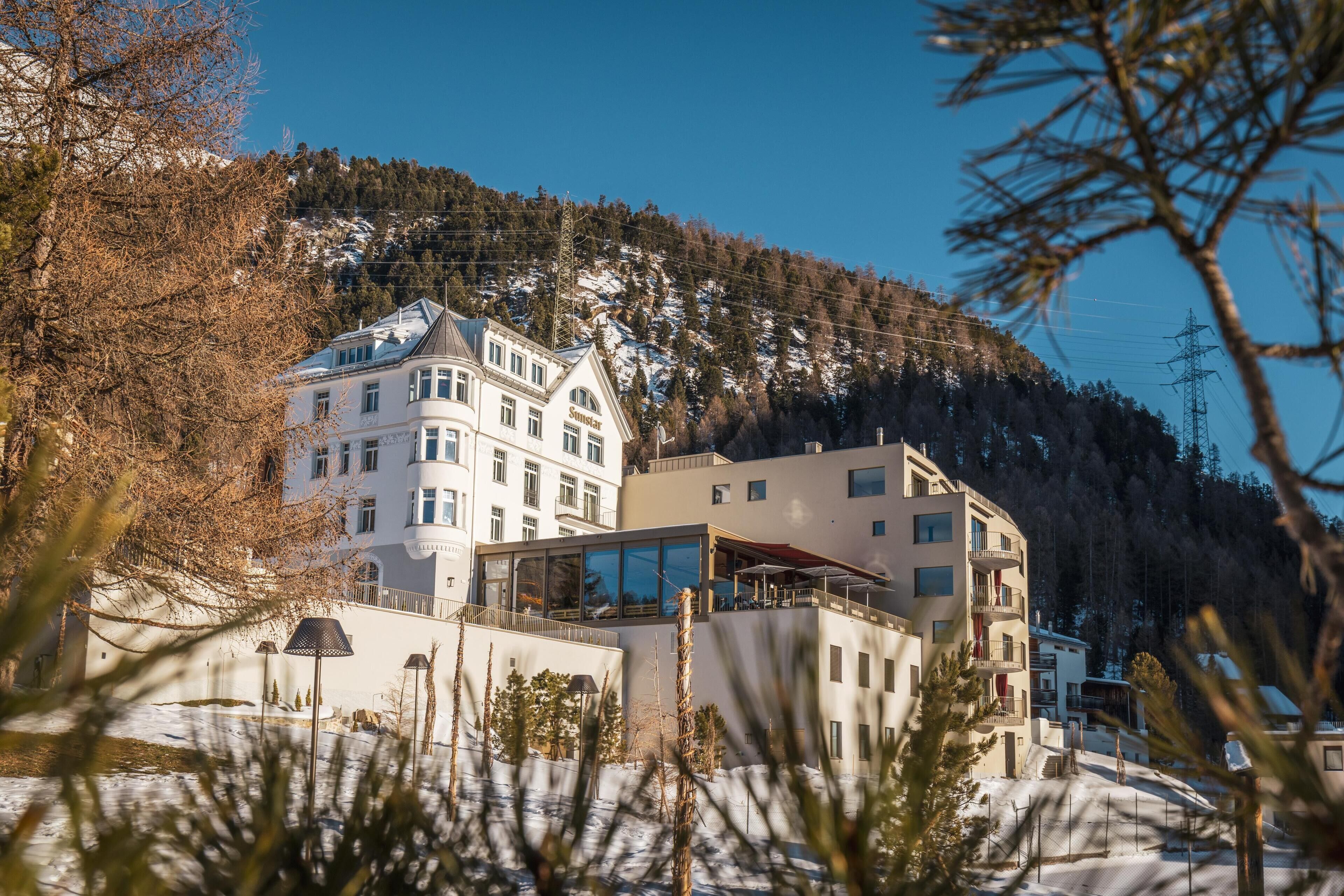 Un hotel de varios pisos, con amplias ventanas y vista a una montaña nevada.