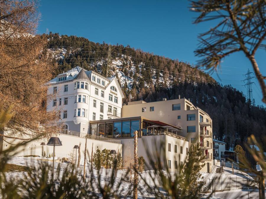 Un hotel de varios pisos, con amplias ventanas y vista a una montaña nevada.