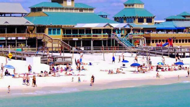 Una località balneare con diversi edifici, una spiaggia sabbiosa e un molo.