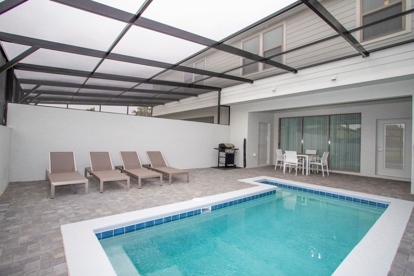 Piscina interior con sillas de descanso y zona de barbacoa.