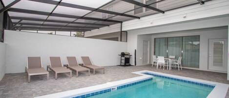 Piscina interior con sillas de descanso y zona de barbacoa.