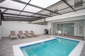 En inomhuspool med solstolar och ett område med grillplats.