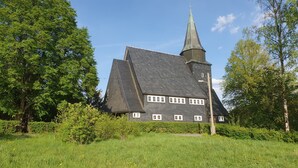 Una chiesa con un tetto spiovente e un campanile slanciato.