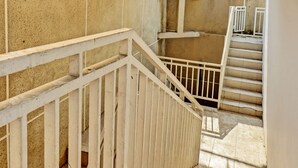 A staircase with white railings and beige tiled walls. - SPOT ON 92916 Batu Mas Homestay Syariah (Jogoroto)