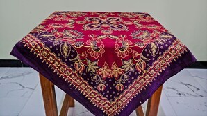 A table with a red and purple tablecloth featuring intricate gold embroidery. - SPOT ON 92916 Batu Mas Homestay Syariah (Jogoroto)