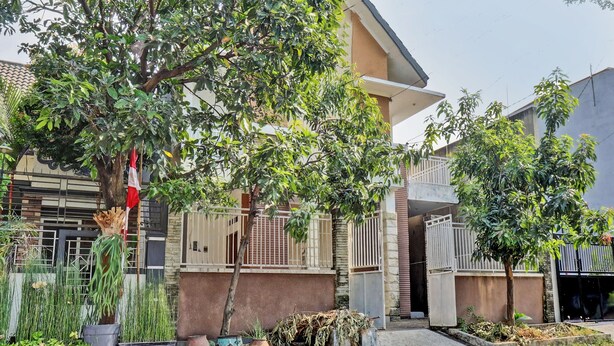 A residential building with a gated entrance, potted plants, and a flag. - SPOT ON 92916 Batu Mas Homestay Syariah (Jogoroto)
