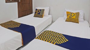 Two single beds with white bedding and blue and yellow patterned bedspreads. - SPOT ON 92916 Batu Mas Homestay Syariah (Jogoroto)