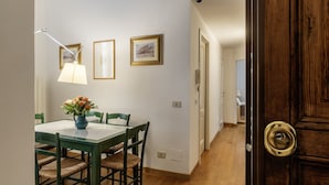 Un coin repas avec une table et des chaises, un vase rempli de fleurs et des tableaux encadrés accrochés au mur.