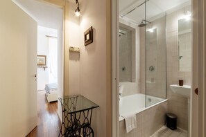 Ein Badezimmer mit einer gläsernen Dusche, einer weißen Badewanne und einem kleinen Glastisch.