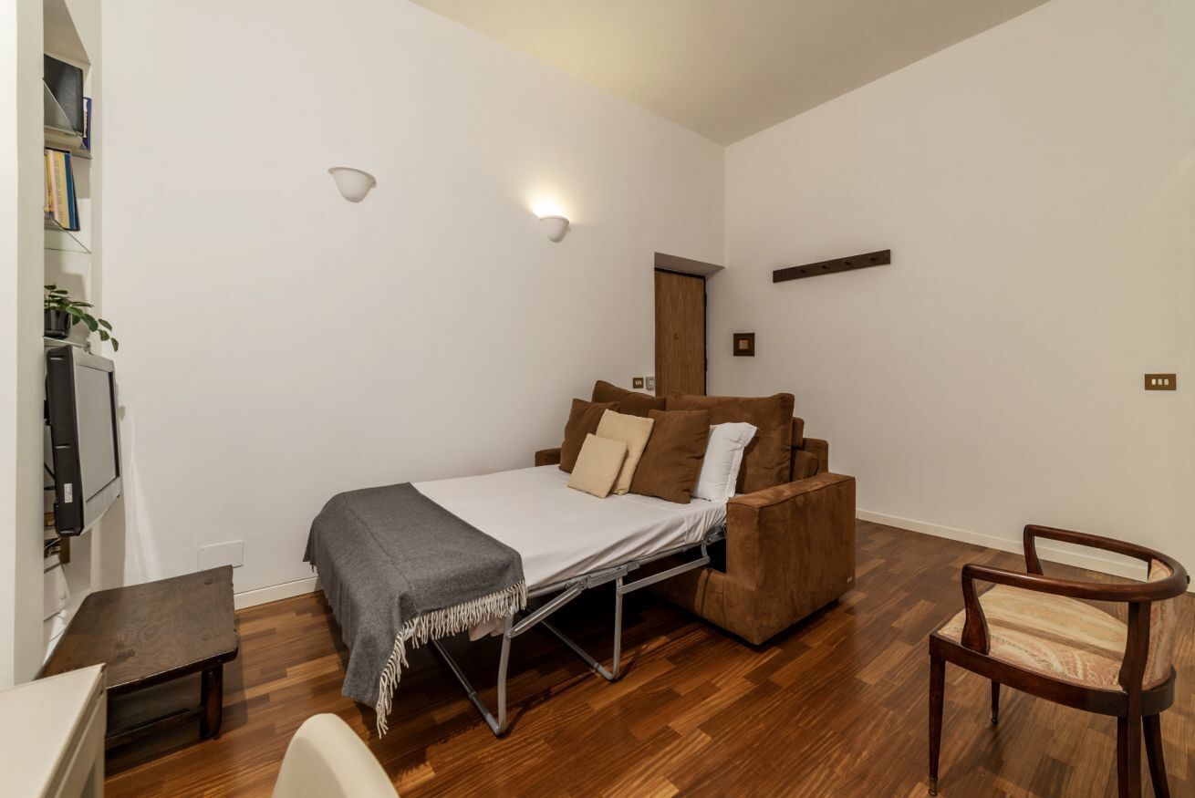 Habitació senzilla amb llit, taula petita, cadira i televisió.