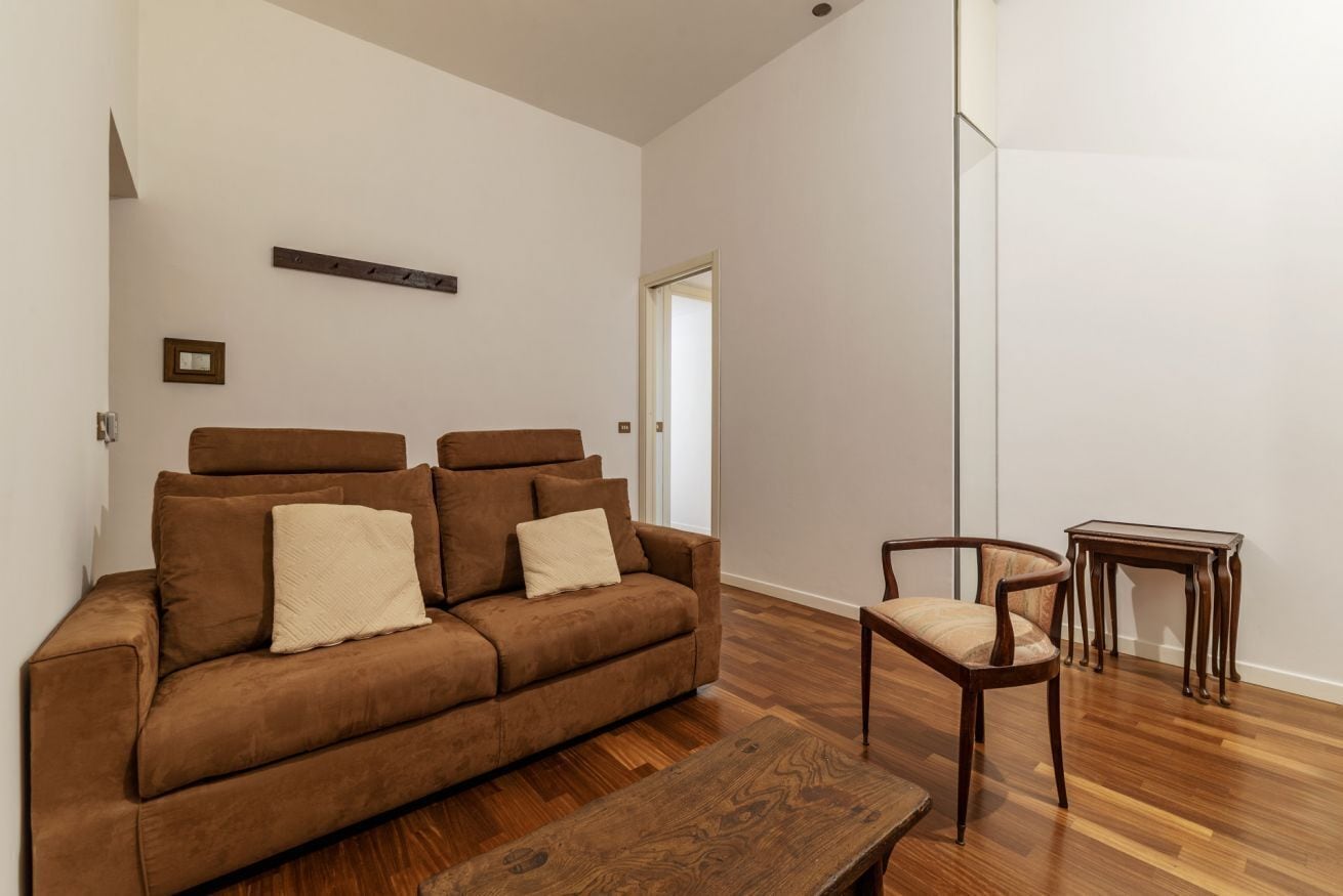 A modern living room with a brown sofa, a wooden coffee table, and a wooden chair.