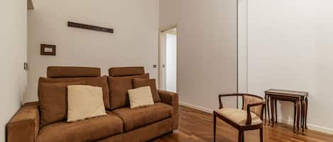 A modern living room with a brown sofa, a wooden coffee table, and a wooden chair.