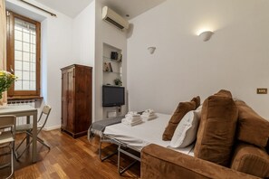 Ein Schlafzimmer mit Bett, Schreibtisch, Stuhl, Kleiderschrank, Fernseher und Bücherregal.