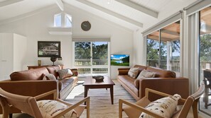 Relax in this stylish living room with a large TV, comfortable sofa, and beautiful views of the outdoors.