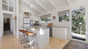Enjoy cooking in this well-lit kitchen with a central island and bar stools, overlooking a lush garden.