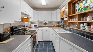 Une cuisine de taille réduite, avec des meubles blancs, un four à micro-ondes, une cuisinière et un évier.