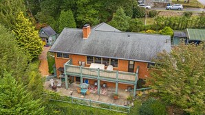 Une maison à deux étages dotée d’un balcon, entourée d’une végétation luxuriante.