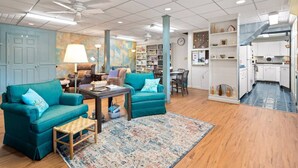Un salon spacieux avec des canapés de couleur turquoise, une table basse en bois et un tapis aux couleurs vives.