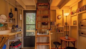 A compact kitchen with a wooden ladder, a sink, and a small dining area with a table and chairs.