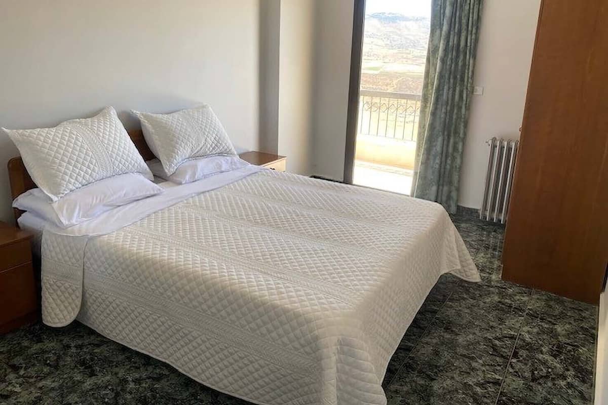 A neatly made bed with white bedding in a hotel room.