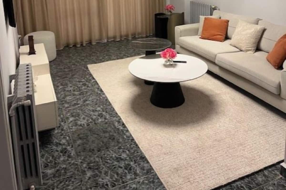 A modern hotel room with a sofa, a coffee table, a radiator, and a television.