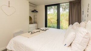 A bedroom with a bed, a ceiling fan, a window with curtains, and a heart-shaped decoration on the wall. - Sun, sea, sand, wind, marram grass – this 4-person chalet embodies the pure beach feeling from your (Burgh-Haamstede)