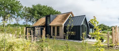 Ein modernes Haus mit Satteldach, großen Fenstern und einem Garten im Vordergrund.